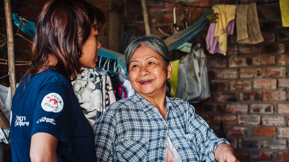 Vietnam Cat Welfare staff member talking to a smiling elderly woman during a community outreach visit